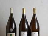 trois bouteilles de vin sont alignées sur une table en bois