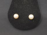 a close up of a pair of pearl earrings on a black surface
