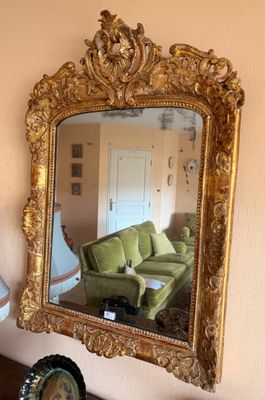 un miroir accroché au mur au-dessus d'une table, à côté d'un canapé vert