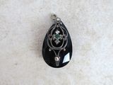 an image of a black stone pendant with a green stone in the center