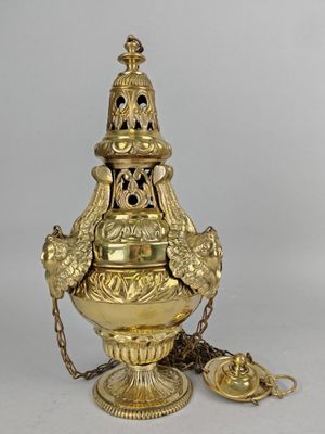 un vase doré entouré d'une chaîne, posé sur une surface blanche