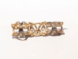 a close up of a gold hair clip on a white surface