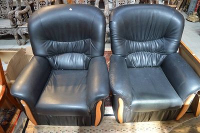 une paire de fauteuils inclinables en cuir noir, avec accoudoirs en bois et repose-pieds