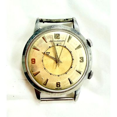 une montre en argent avec un cadran jaune sur fond blanc