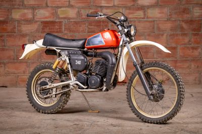 a red and white dirt bike parked in front of a brick wall