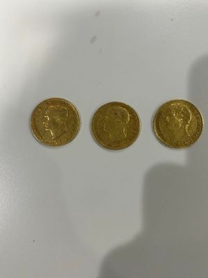 three gold coins sitting next to each other on a white surface