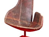 un fauteuil en cuir marron avec un piètement rouge sur fond blanc
