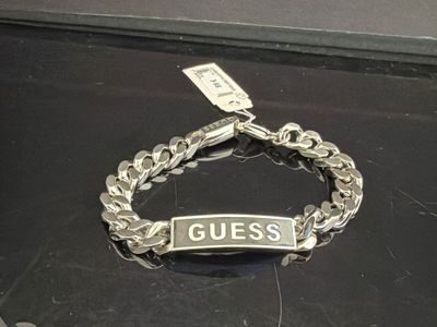 un bracelet en argent sur lequel est inscrit le mot « guess »