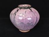 un vase violet posé sur une surface noire