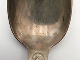 a silver spoon with a handle on a white surface