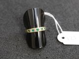 une image représentant une bague sertie d'émeraudes sur un fond noir