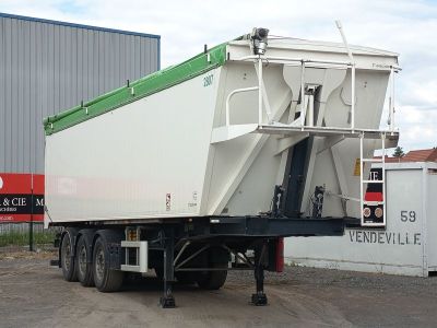 un camion blanc avec un toit vert garé devant un immeuble