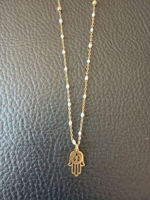 a gold hamsa necklace with pearls and a small hamsa charm