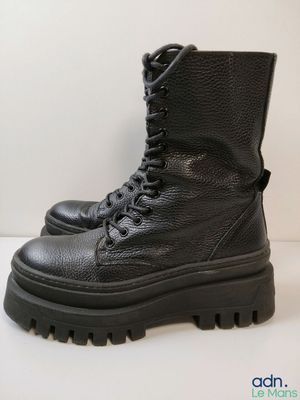 un gros plan sur une paire de bottes noires posées sur une surface blanche