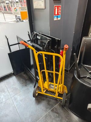 un diable jaune qui se trouve à côté d'une poubelle noire