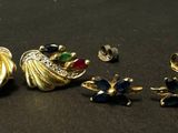 two pairs of earrings and a ring on a black surface