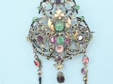 silver broochle with multi colored stones on it on a blue surface