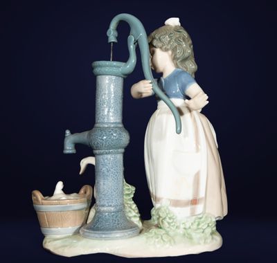 une figurine représentant une femme avec un seau et une pompe à eau