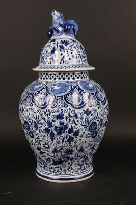 blue and white vase with a bird on top of it on a table