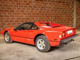 a red sports car parked in front of a brick wall