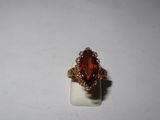 a close up of a ring with an orange stone in it