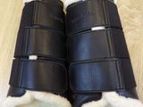 pair of black leather boots with sheepskin linings on a wooden floor