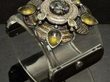 silver and gold cuff bracelet with yellow stones on a black surface
