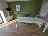 a white desk with a black chair and a map on the wall