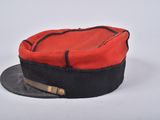 red and black military hat with leather band and brass buckles