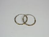 two gold hoop earrings on a white surface