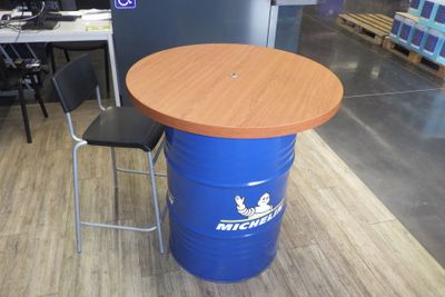 un tonneau bleu surmonté d'un couvercle en bois, posé à côté d'une chaise noire