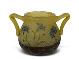 yellow vase with blue flowers on it sitting on a white surface