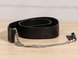 une ceinture en cuir noir avec une chaîne en argent posée sur une table en bois