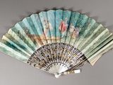 a fan with a painting on it hanging on the wall