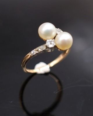 gros plan d'une bague en perles et diamants sur une surface noire