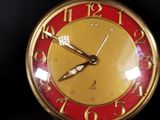 a red and gold clock on a black surface