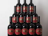 Plusieurs bouteilles de vin rouge sont posées sur une table devant un mur blanc.