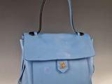 un sac à main en cuir bleu orné d'un emblème doré sur le devant