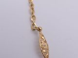 a close up of a gold necklace with a leaf on it
