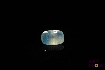 a close up of a ring with a blue stone on a black surface