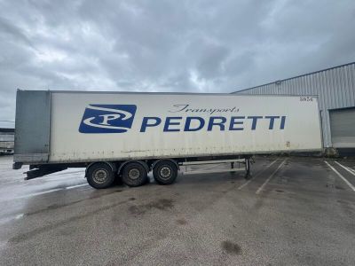 the semi trailer is parked in front of a large building