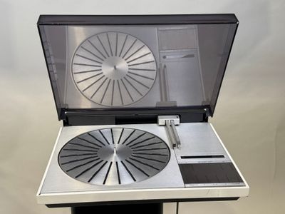 une platine vinyle argentée et noire sur laquelle est posée une horloge