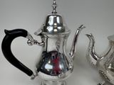 two silver teapots sitting next to each other on a table