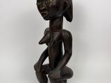 a wooden statue of a woman with a hand on her chest