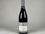 une bouteille de vin rouge posée sur une table blanche