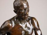 bronze statue of a man holding a tennis racquet on a marble base