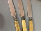 three knives on a table next to a bunch of bananas