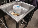 a metal sink with a bucket on it in a room