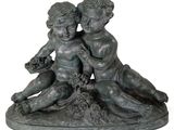 statue of two children sitting on a rock with flowers in their hands