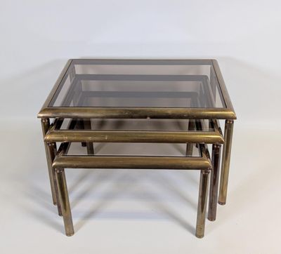 a set of three brass nesting tables with glass tops
